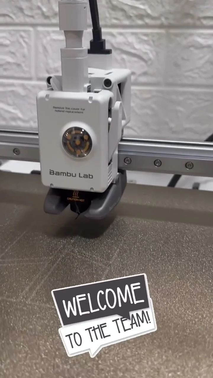 手持兩件黑色 3D 打印零件，檢查表面的淺藍色凸字
