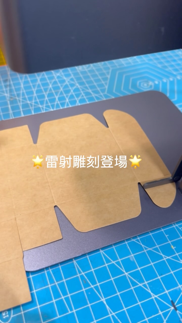 雷射雕刻工作中的畫面：牛皮紙色禮盒放喺切割機平台上，旁邊有「雷射雕刻登場」字樣
